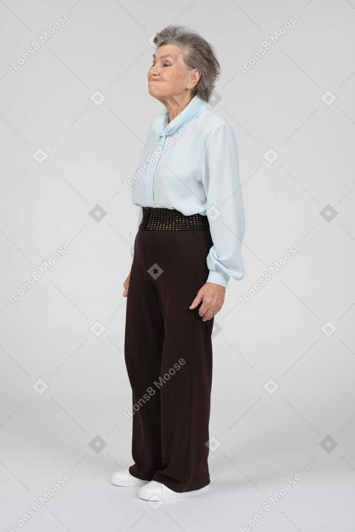 Вид в три четверти на пожилую женщину, надувающую щеки