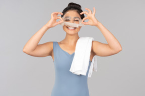 Young indian woman with white towel on shoulder peeling off face mask