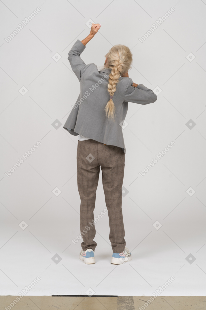 拳を示すスーツを着た老婦人の背面図