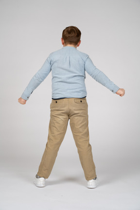 Rear view of a boy standing with outstretched arms
