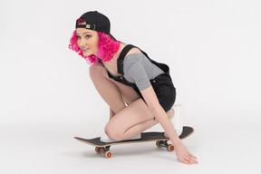 Ragazza allegra cavalcando uno skateboard in ginocchio