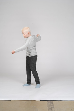 Blond boy in casual clothes spinning around