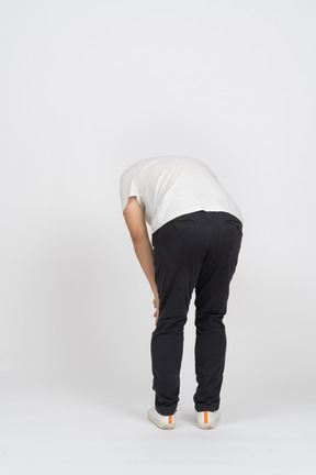 Back view of a man bending down and touching knee