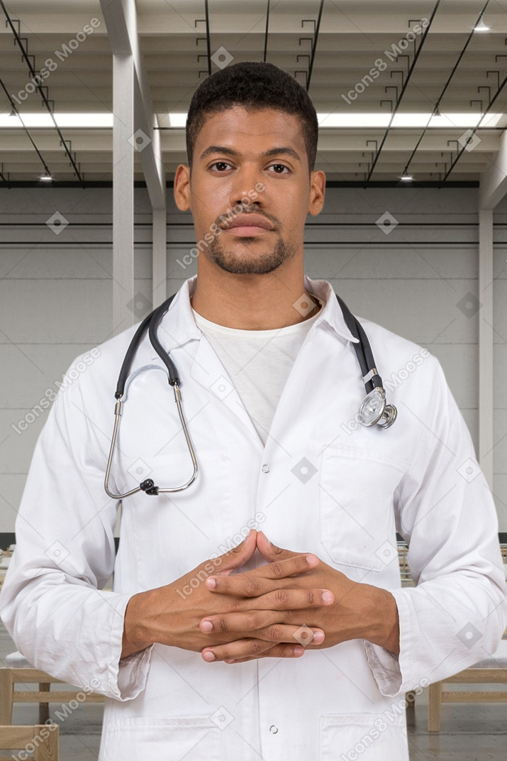 A man in a white lab coat standing with his hands folded