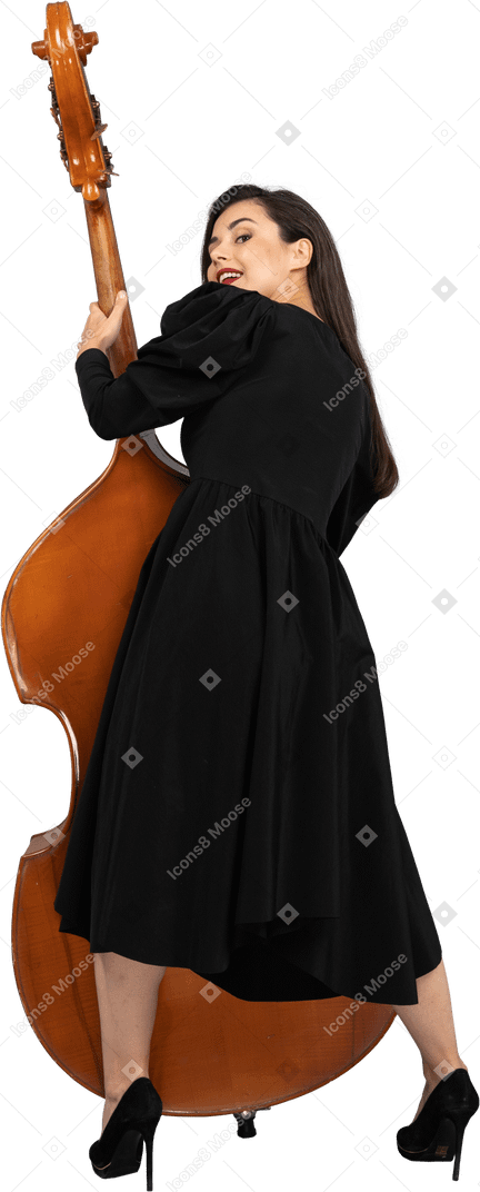 后视图的高兴的年轻女音乐家，穿着黑色的连衣裙，抱着她的双低音