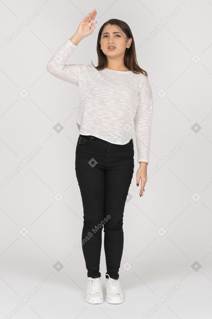 Front view of a perplexed young indian female in casual clothes raising hand