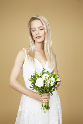 Schöne braut, die einen hochzeitsblumenstrauß von weißen blumen hält