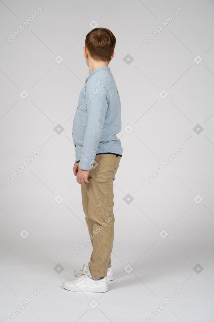 Мальчик в повседневной одежде стоит в профиль