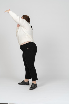 Vista lateral de una mujer regordeta en ropa casual con brazo levantado