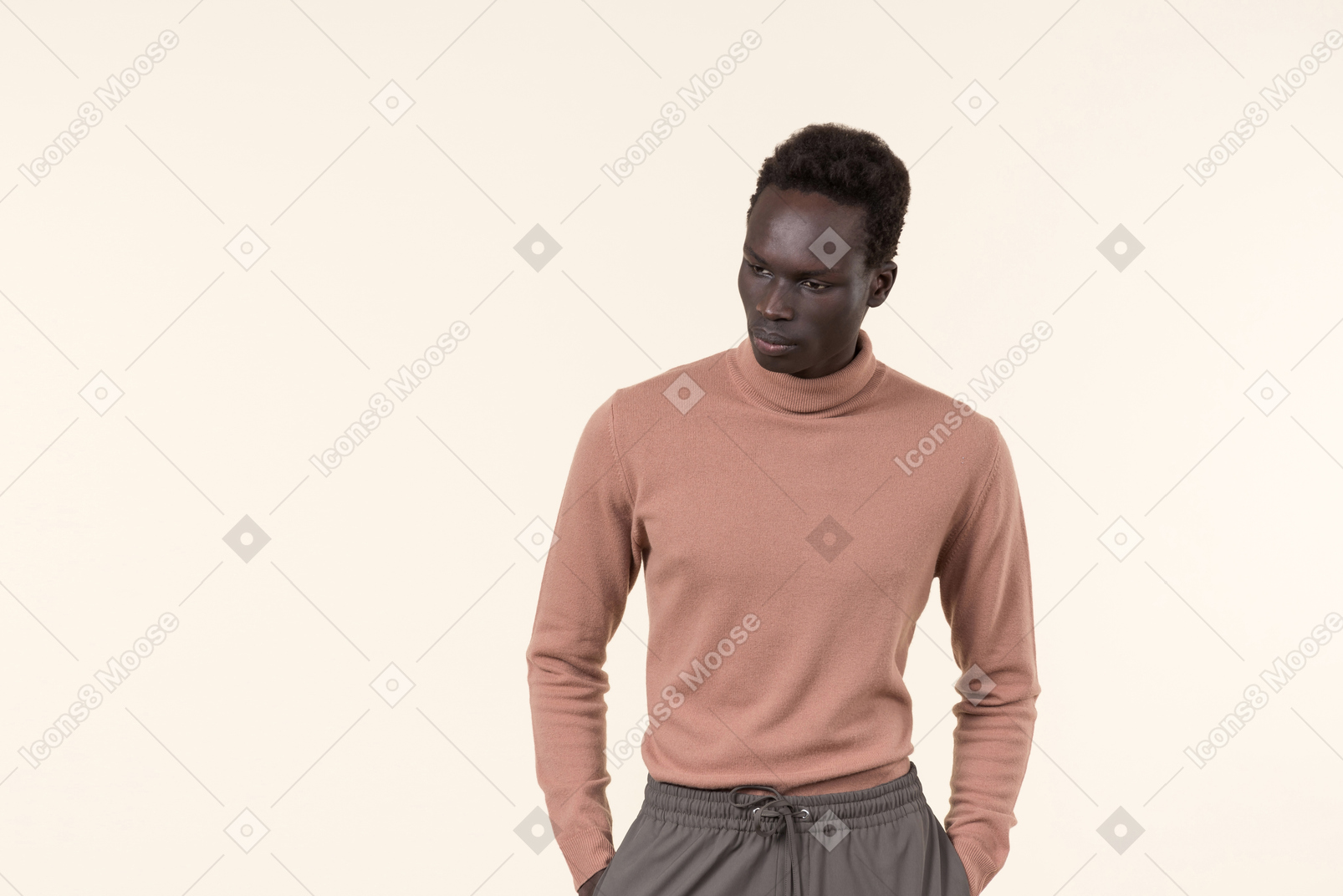 Ein junger schwarzer mann in einem beigen rollkragenpullover und einer grauen jogginghose, die lässig auf dem weißen hintergrund stehen
