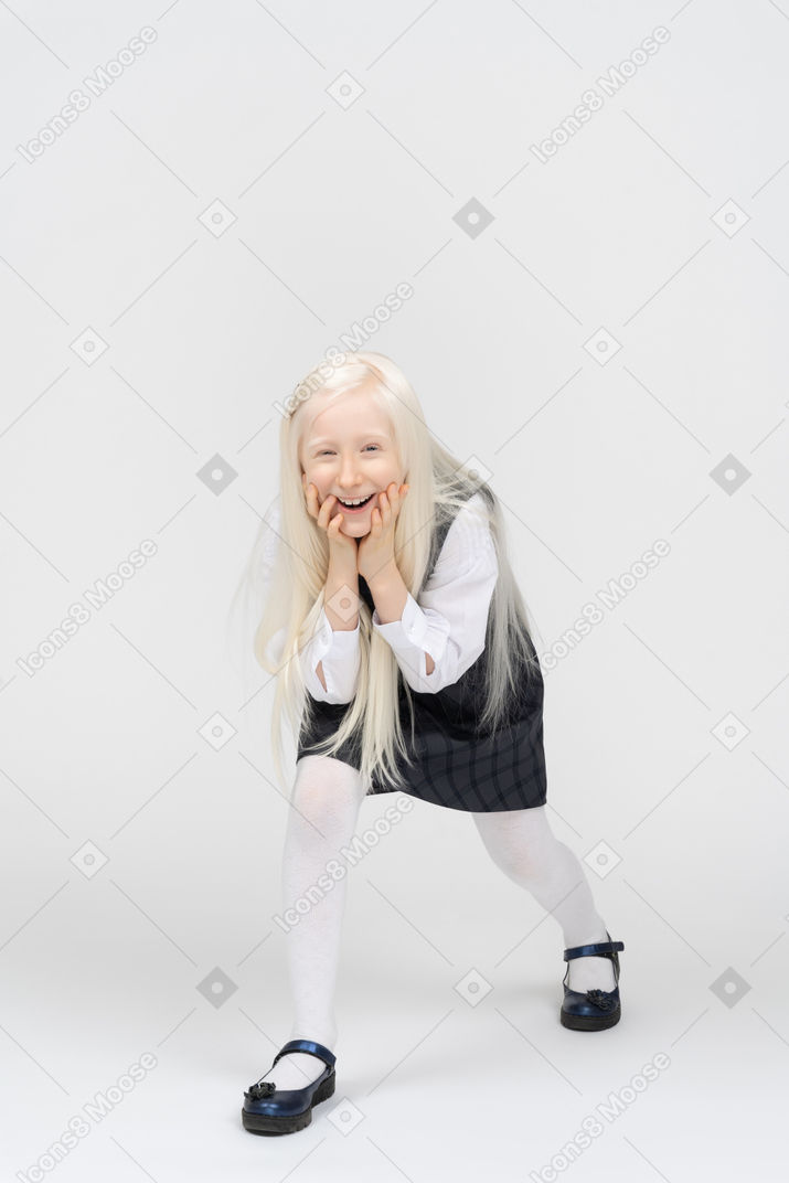Schoolgirl holding her face with both hands and laughing