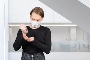 Woman in face mask applying hand sanitizer in a room