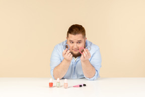 Big man looking attentively at hair bands he's holding