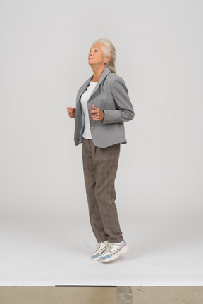 Side view of an old lady in suit jumping