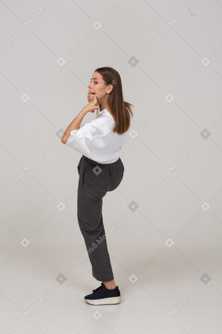 Vista posteriore di tre quarti di una giovane donna con una smorfia in abiti da ufficio office