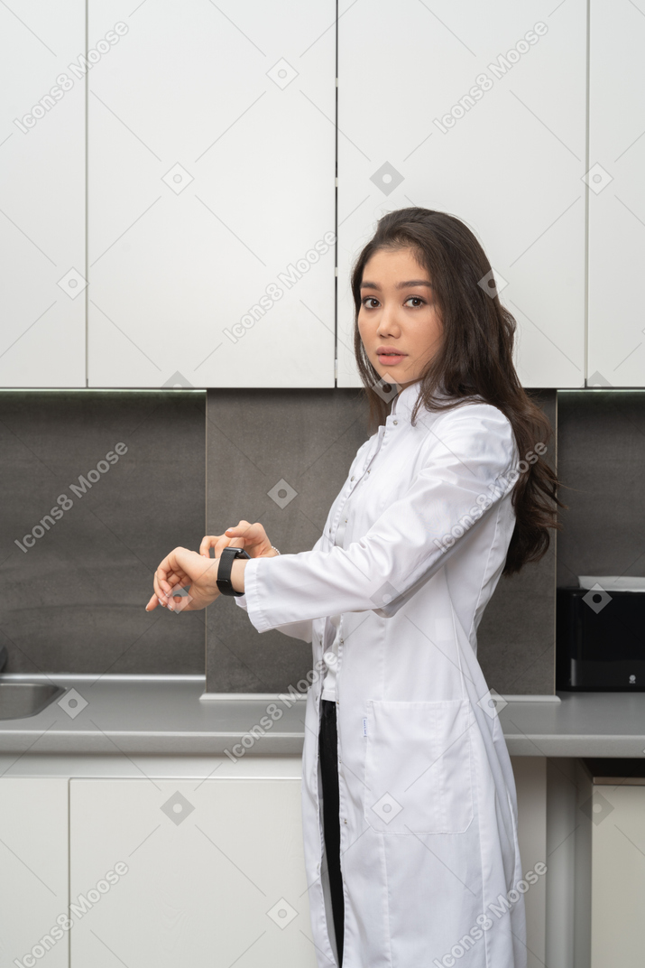 Side shot of a female doctor checking time and looking the camera
