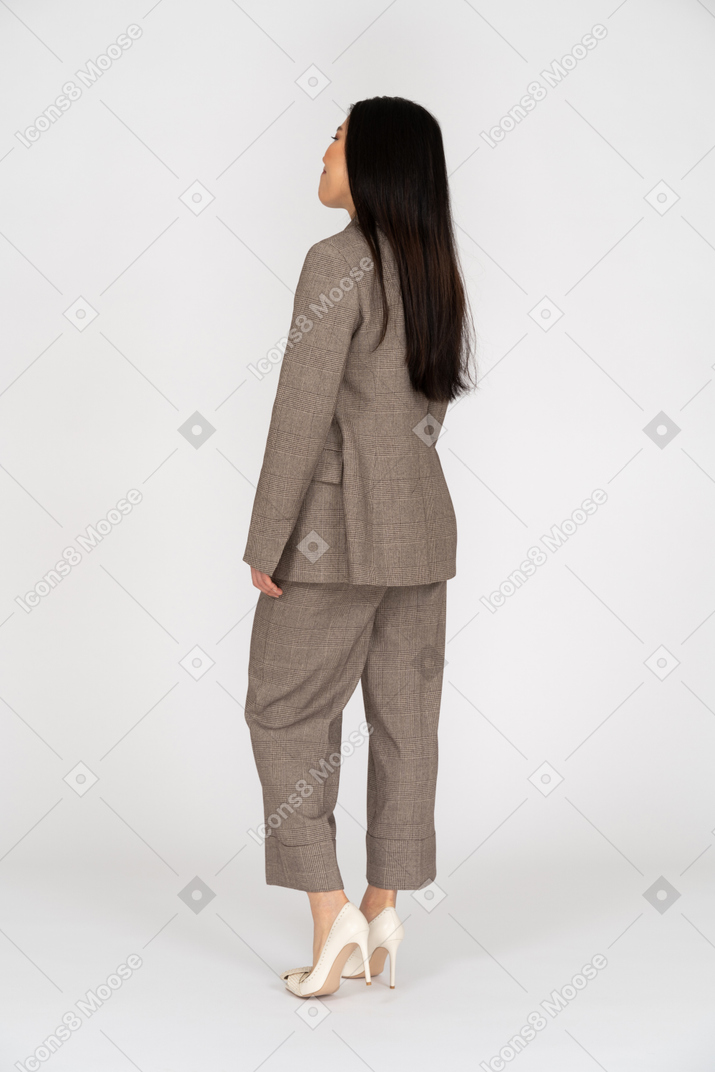 茶色のビジネススーツを着た笑顔の若い女性の4分の3の背面図