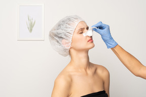 若い女性の鼻の包帯を取り除く医師