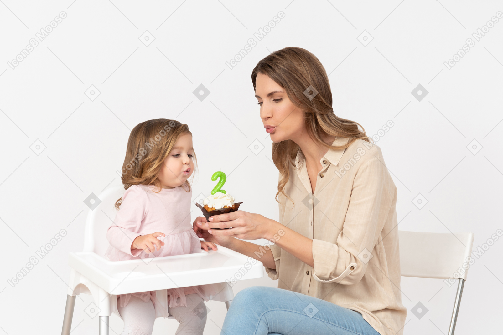 Baby girl blowing off a candle as her mother's holding a birthday cake