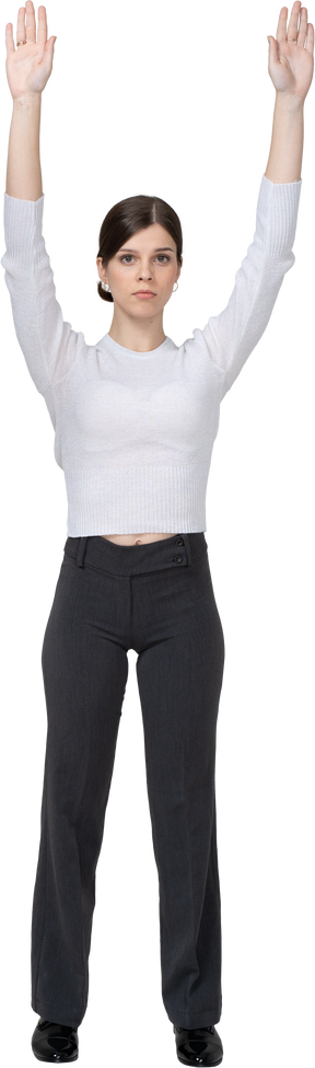 Front view of a young woman in office clothing raising hands