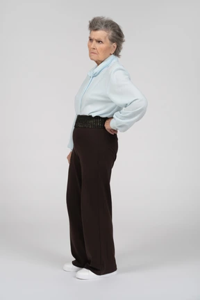 Side view of an old woman frowning with a hand on the hip