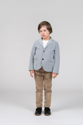 A young boy wearing a gray jacket and khaki pants