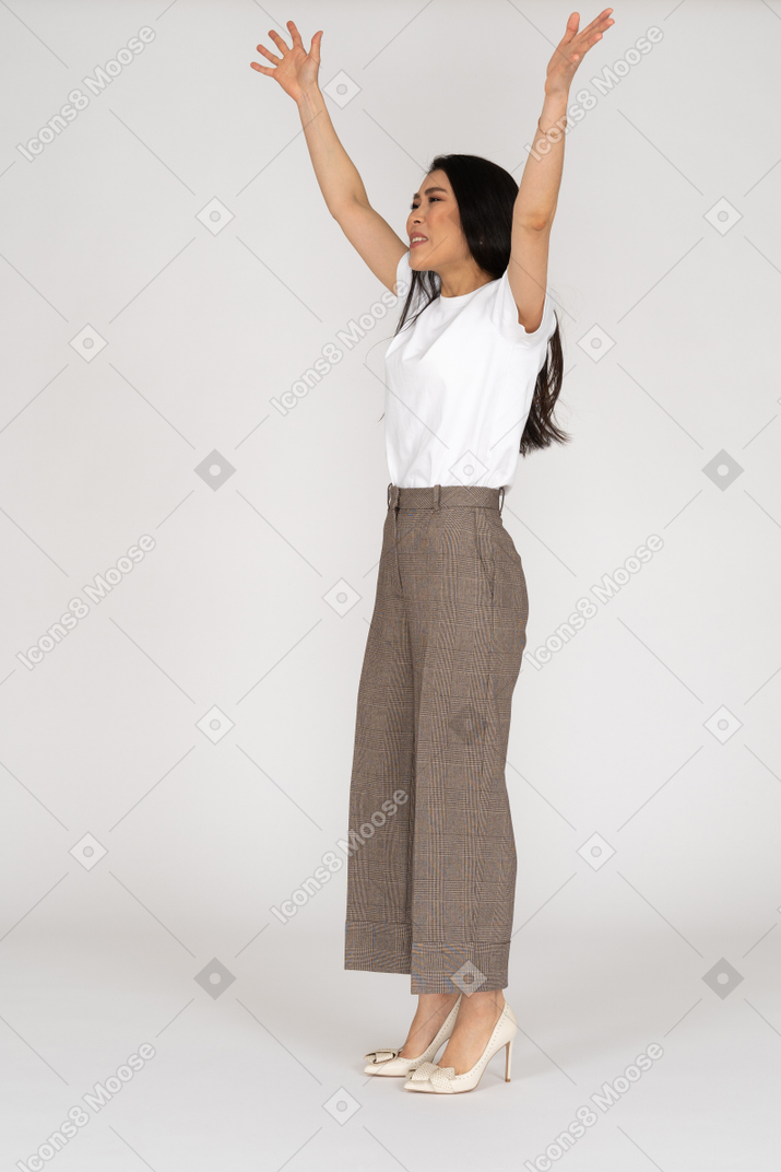 Three-quarter view of a young lady in breeches and t-shirt raising hands