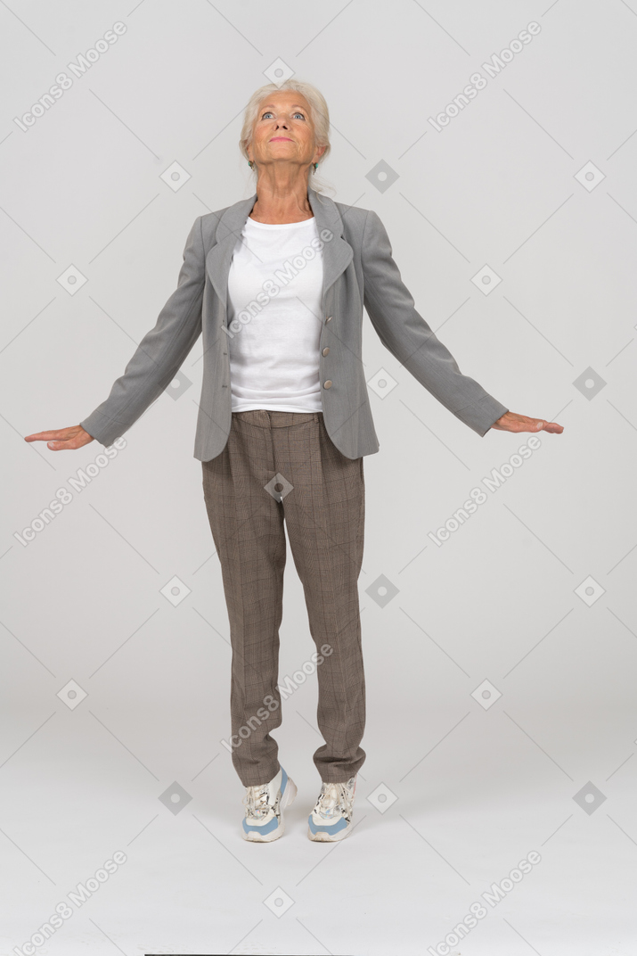 Front view of an old lady in suit standing on toes and outspreading arms
