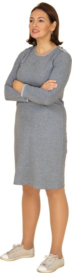 Front view of a woman in grey dress standing with crossed arms