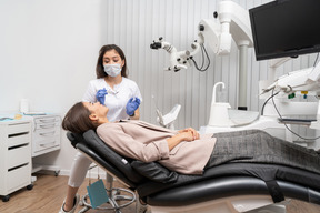 Comprimento total de uma dentista consultando sua paciente em um armário de hospital