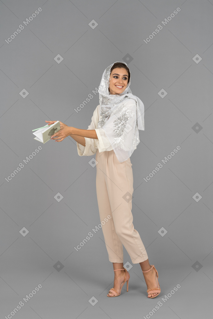Smiling muslim woman holding an open notebook