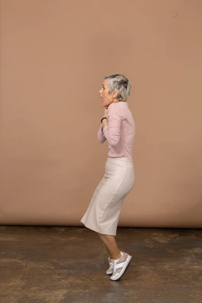 Side view of an impressed woman in casual clothes standing on toes