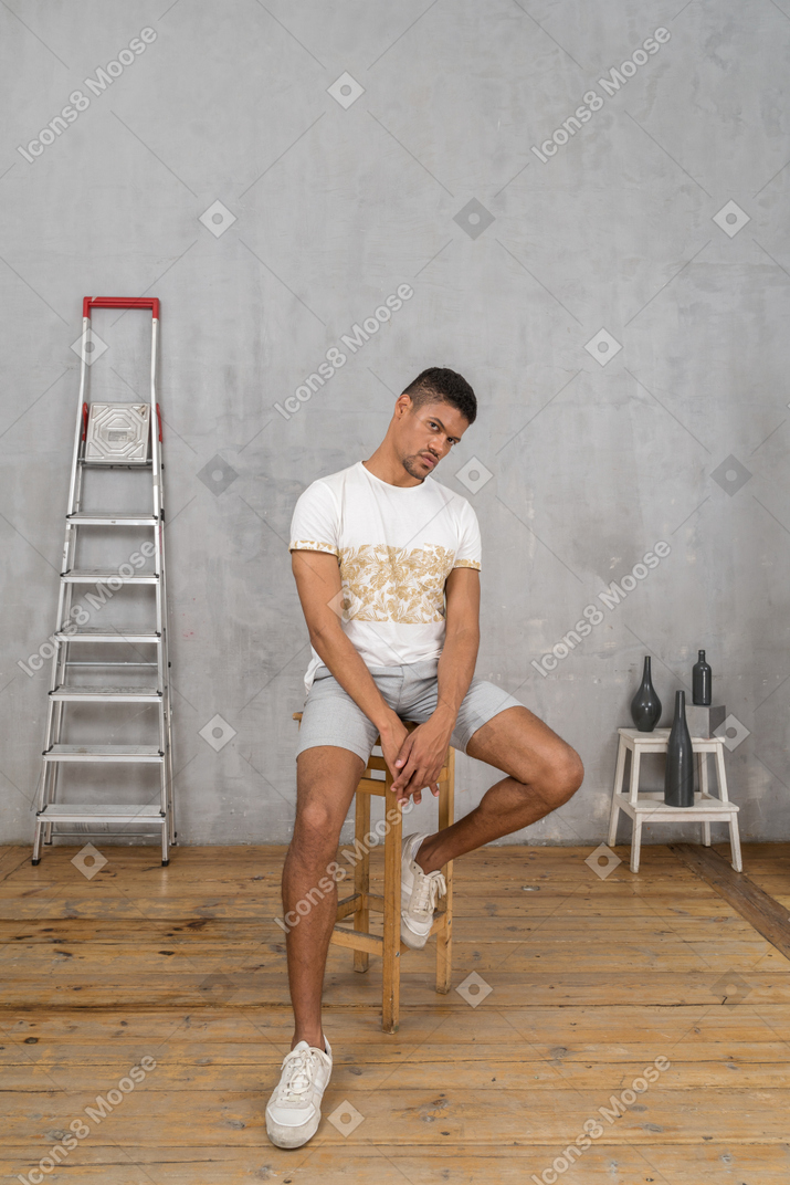 Молодой человек в повседневной одежде сидит на стуле