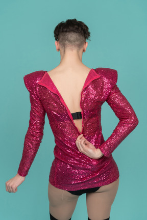 Vista traseira de uma drag queen abrindo o zíper do vestido rosa