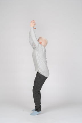 Side view of a boy trying to jump with hands raised
