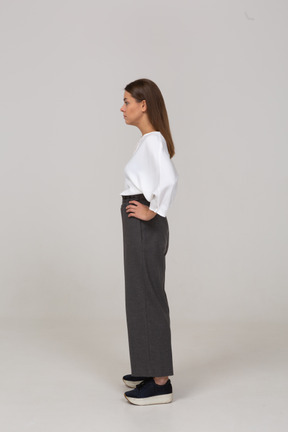 Side view of a serious young lady in office clothing putting hands on hips