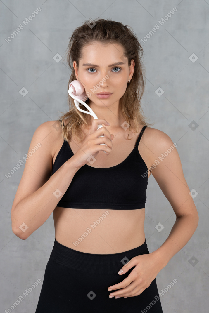 Front view of a young woman massaging her face with a face roller