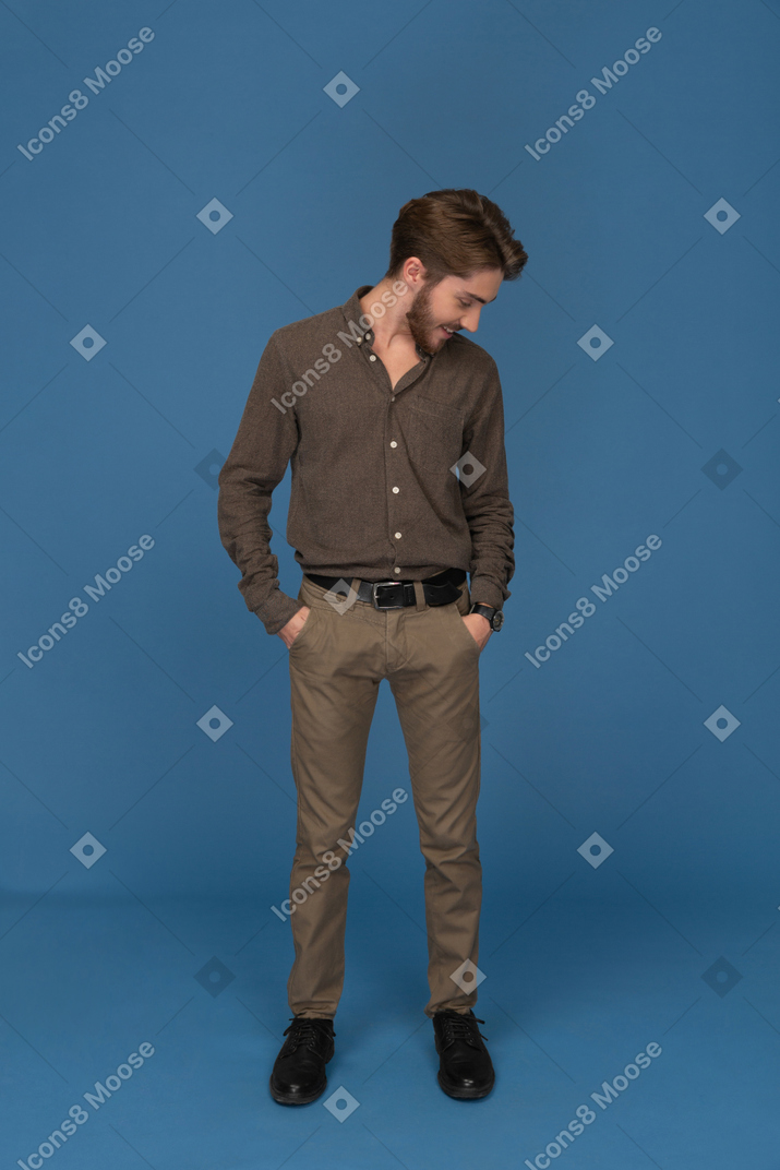Pleased young man standing with hands in pockets