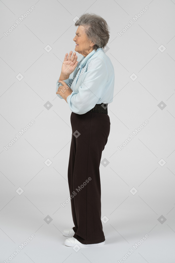 Old woman with closed eyes and raised hand