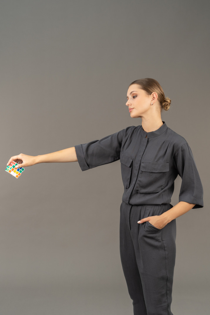 Three-quarter view of young woman in a jumpsuit holding a rubik's cube