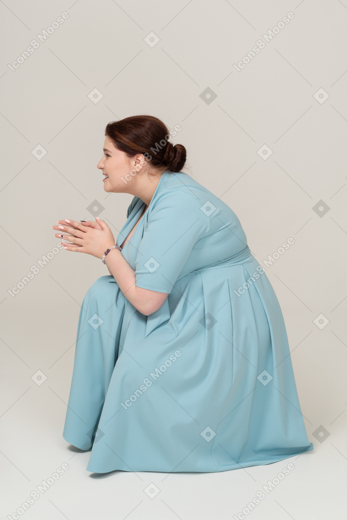 Vista lateral de uma mulher de vestido azul agachada
