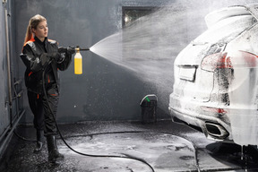 Молодая женщина моет машину