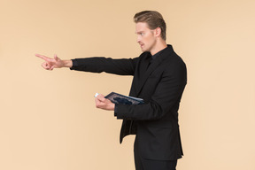 A white man in a fully black suit holding the quran