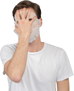 Front view of a young man taking off his facial mask