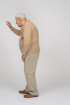 Vista lateral de un anciano con ropa informal que muestra el tamaño de algo
