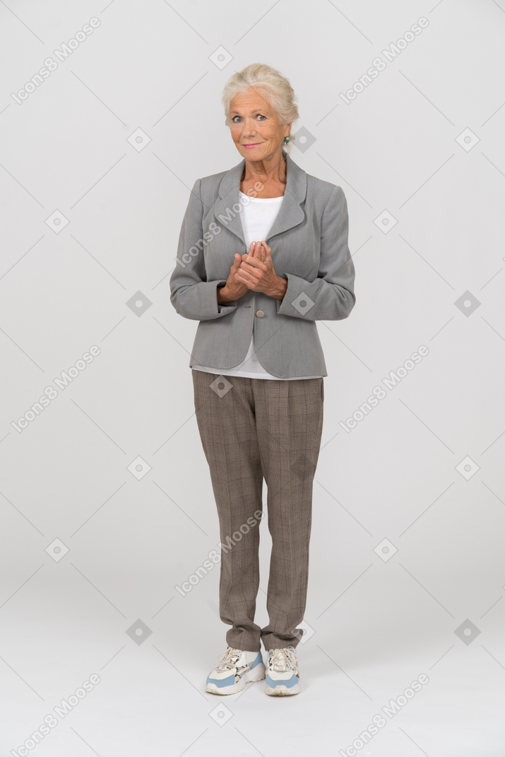 Vorderansicht einer glücklichen alten dame im anzug, die in die kamera schaut