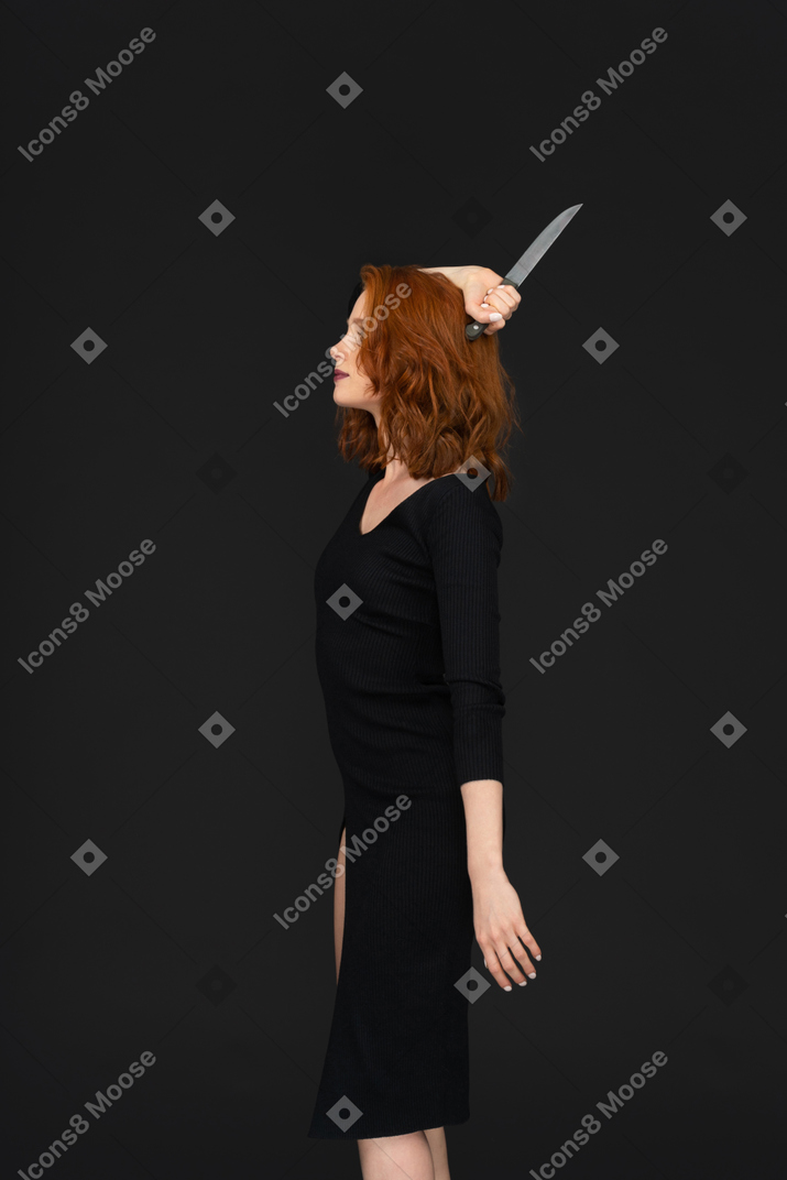 A side view of the beautiful young woman posing with a knife