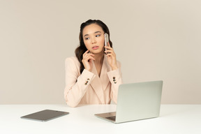 Employé de bureau asiatique impliqué dans une conversation téléphonique