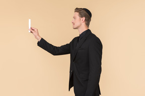 Young man in a black suit and a kippah holding a candle