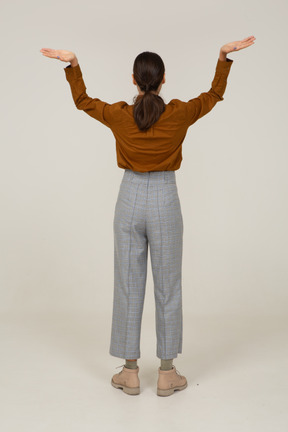 Back view of a young asian female in breeches and blouse raising hands